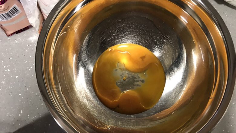 巧克力淋面蛋糕,先处理蛋黄部分。加入食用油,用手动打蛋器搅拌均匀。