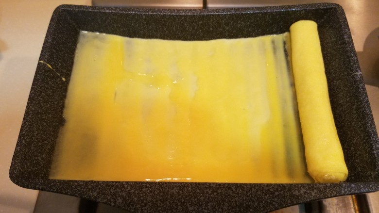 樱花玉子烧,把卷好的蛋卷移到锅子左边,再继续煎第二层,按此方法一共卷三层。