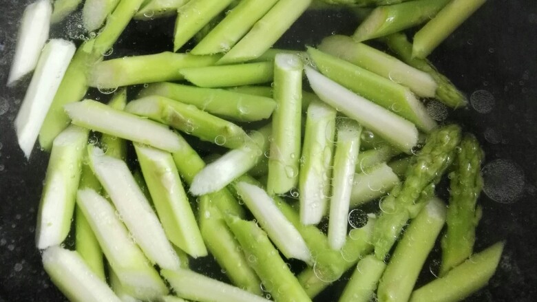 芦笋虾仁,锅里水烧开给点盐和油,倒入芦笋汆烫一下