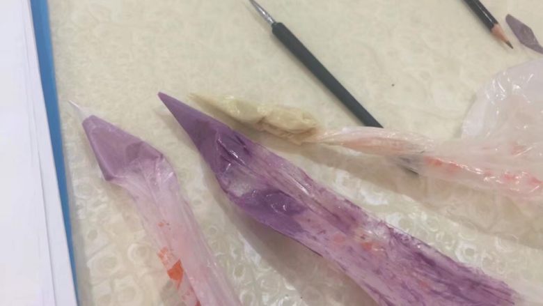 【拨浪鼓】手绘蝴蝶紫薯慕斯蛋糕,调出填充图案的深浅不同的<a style='color:red;display:inline-block;' href='/shicai/ 9684'>奶油霜</a>,装入裱花袋。