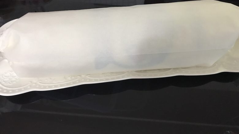 哆啦A梦彩绘蛋糕卷,卷好的蛋糕卷用油纸包好,图案朝上,放冰箱冷藏定型。至少冷藏半小时。