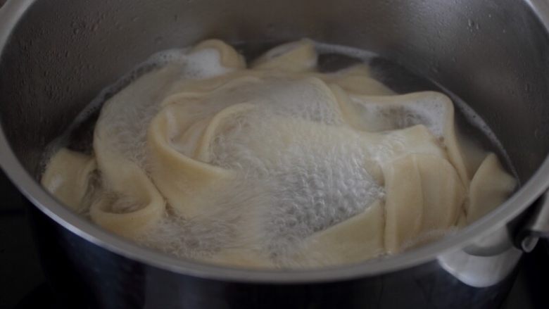 大盘鸡,13.将醒好的面用手捏扁,拉成长条,下入滚水锅中。