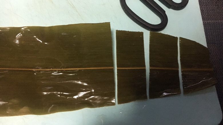 五彩糯米排骨卷,粽叶铺平,从三分之一处剪成三段,舍弃最顶端不要,剪的宽度和小排的宽度相同