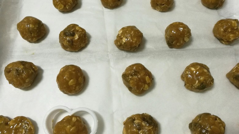 红糖燕麦葡萄饼,捏一块面糊,搓成圆形,放在垫有油纸的烤盘上。