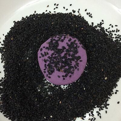 烤紫薯糯米饼,将饼坯放在芝麻上,两边都均匀的沾上芝麻