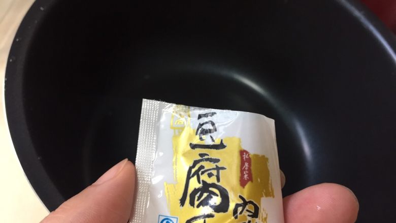 自制爽滑豆花,把三克内酯倒进电饭煲，用30克左右的温开水化开放一边备用。
温开水不需要太多，能化开内酯就可以了。