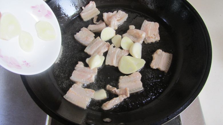 扁豆焖面,煸炒至五花肉微微出油时加入蒜片;