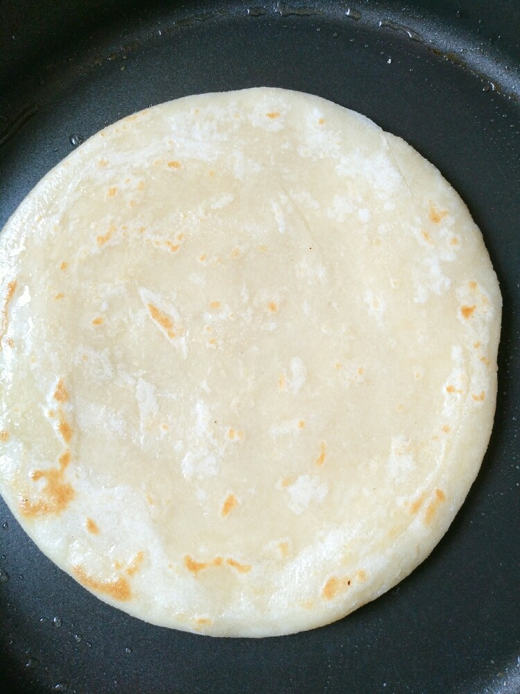 千层油饼,提前热锅后抹少许油(油一定不要放多,放多了可以用厨房纸吸出来),放入饼胚,先快去烙大约半分钟至底部稍微定型赶紧翻面烙至稍微上色,锁住饼内水份。(第一次翻面不能时间太长,以免靠干水份,使烙出的饼干硬)