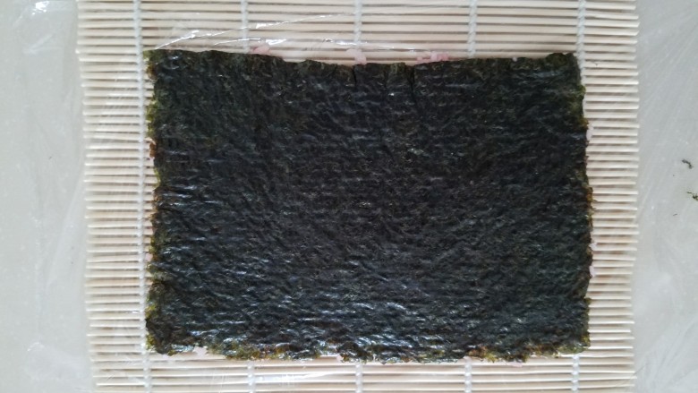 樱花寿司,压好后保鲜膜就粘在米饭上了,然后翻转过来,保鲜膜在下成,海苔在上面。