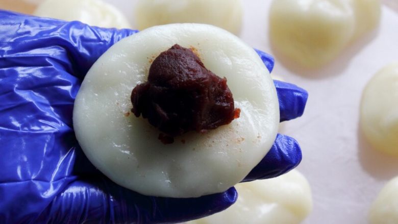 闽台风味茶点心豆沙糯米糍,10.取一份,按成圆饼。
放一小勺豆沙在中间。