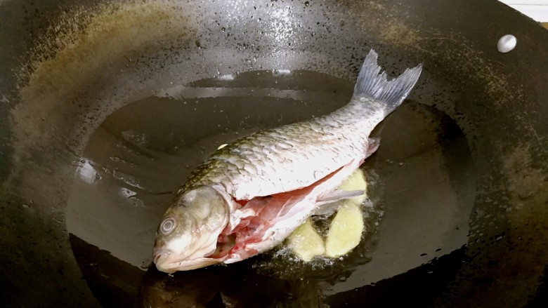 豆腐鲫鱼汤,倒入食油,鲫鱼滤干表面水分,摆入锅中,小火煎制。