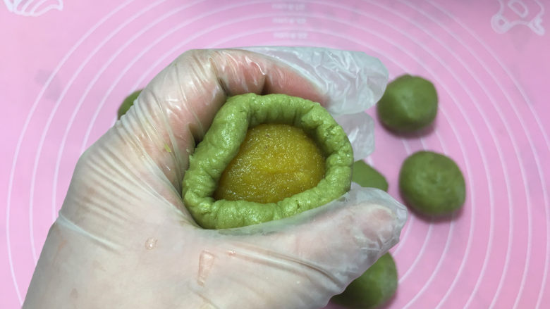 樱花抹茶凤梨酥,放入凤梨馅,借助左手虎口和右手转动将口收紧。