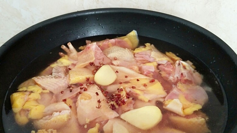 家常烧大盘鸡,鸡肉斩块,放入锅中注水,放入姜片,花椒粒适量煮开,辍水