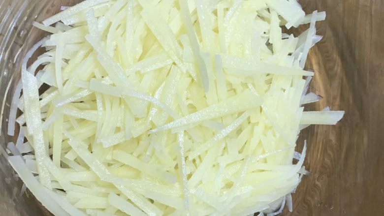 凉拌酸辣土豆丝,把土豆丝挤干水份放入大碗中