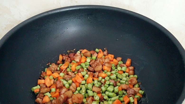 豇豆卤肉焖饭,倒入胡萝卜丁和豇豆,翻炒均匀断火备用。