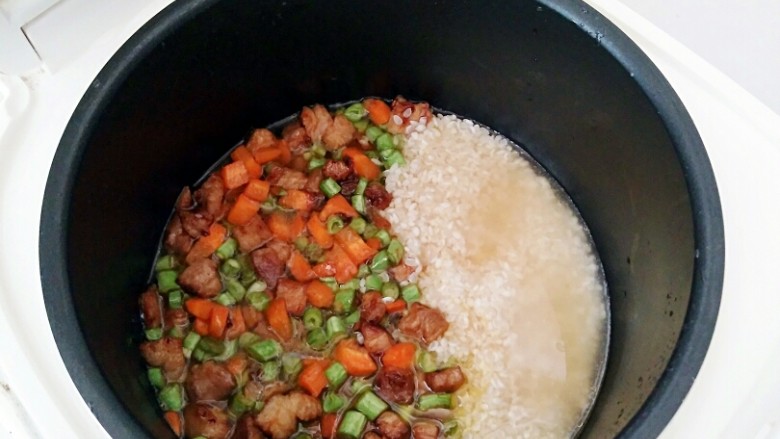 豇豆卤肉焖饭,倒入清水,水量刚好和食材齐平,在上面撒上盐。