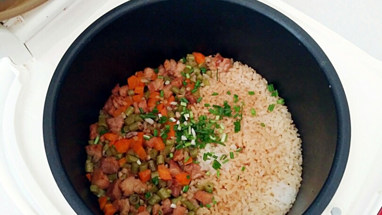 豇豆卤肉焖饭,滴声响起煮饭完成,撒上香葱碎,翻拌均匀即可出锅。