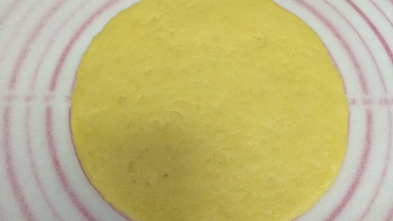 红豆葡萄干松饼,将面团分成两份,放一张油纸,取一份面团在油纸上擀成圆形的饼状。