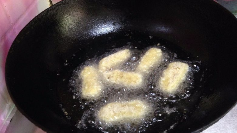 脆皮炸鲜奶,锅里倒入适量油烧至六成热,将挂满糊的奶块逐个放进去炸到表面金黄