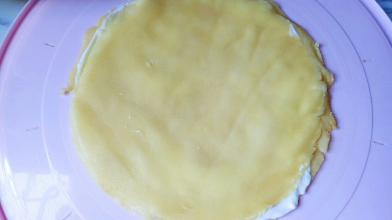芒果千层蛋糕,取一块大盘子,我用的是蛋糕盒子的底部,最底层放两张蛋皮,抹上奶油馅,在奶油馅上放一些芒果肉,再盖上一张饼皮,再涂抹奶油馅,放芒果肉。重复同样的步骤 至饼皮做完。