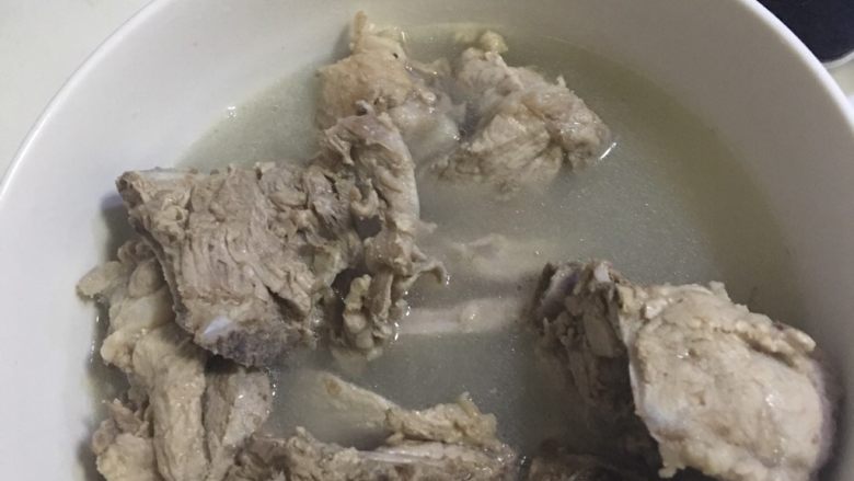 正宗东北酸菜炖大骨头,将煮脊骨盛在碗中,将锅中上面的汤倒出,留下二分之一倒入盛骨头的碗中。