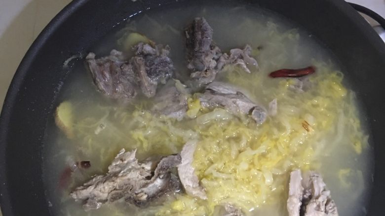 正宗东北酸菜炖大骨头,将猪脊骨,原汤、适量冷水倒入锅中煮沸。
