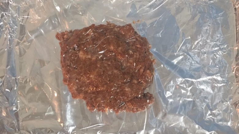 蜜汁黑胡椒豬肉乾,烤盤鋪鋁箔紙,且鋁箔紙要比烤盤大過一些,這樣烤的時候醬汁才不會流到烤盤上.烤箱預熱到150度!
然後取1/3量的絞肉放在鋁箔紙(亮面朝上)的中間,上面蓋一層保鮮膜,接著用桿麵棍將絞肉均勻的桿平成烤盤大小. 註:此食譜可以烤出三片