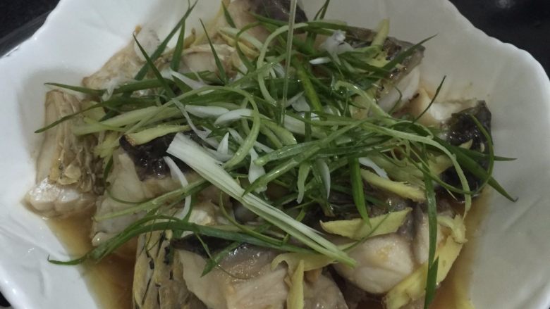 酱香蒸鲩鱼腩,10. 蒸到12分钟时把调味菜码在鱼面上,最后加上一勺花生油,盖上盖子,再蒸一分钟,即可出锅