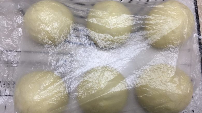 一次发酵椰香绵绵吐司,将面团分成3等份,揉圆后盖保鲜膜静置10分钟(一次做两份,所以图片是6等份)