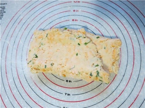 超快速面包--切达芝士香葱司康,硅胶案板上撒薄面将面团至于案板上,采用擀开折叠按压的方法折叠2次,不要用手揉。