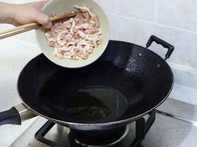 鱼香肉丝,干净的空锅置于大火上烧热,锅刚要冒烟的时候倒入约小半碗冷油,油稍微泛波澜时转小火,倒入肉丝。