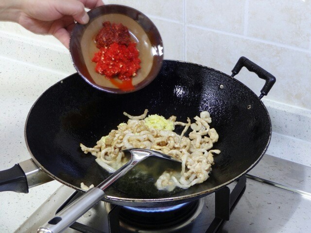 鱼香肉丝,当肉丝快要断生之际,用锅铲把肉丝铲至锅中一旁,尽量留出空油,转为大火,先倒入姜蒜粒沾油爆一会儿,再加入豆瓣酱和泡红椒碎一块爆一会儿。
