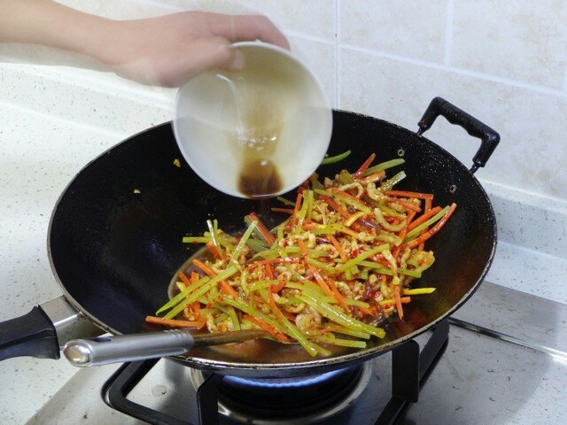 鱼香肉丝,约两分钟后胡萝卜丝和莴苣丝断生,就将调好的糖醋汁沿锅边倒入。