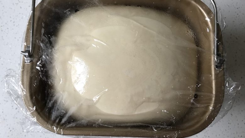 香葱培根芝士面包(咸香味),将面团放入容器中,盖上保鲜膜。进行基础发酵至两倍大。(当室温高于28度时应当选择放入冰箱冷藏发酵。室温25度左右可以选择室温发酵。冬季室温较低,选择放入烤箱,不盖保鲜膜,烤箱内放入温水,开启发酵功能发酵,发酵温度设定28度。如果烤箱发酵温度较高,可以不开发酵功能,直接用温水保证烤箱内温度和湿度即可。烤箱内壁水汽不流下说明湿度合适。)