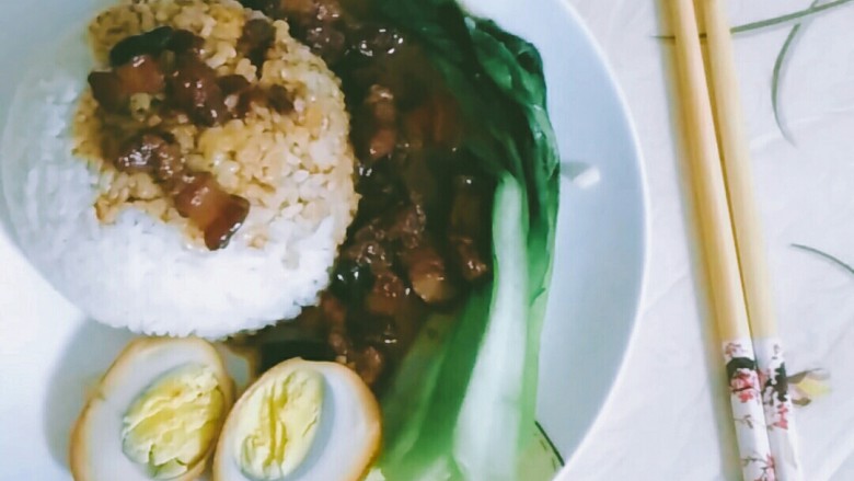 自制卤肉饭,取一小碗把饭盛满,压实倒扣在盘中,舀入卤肉和汁,放入对切的鸡蛋,摆入清炒好的青菜。(慢慢享用吧)