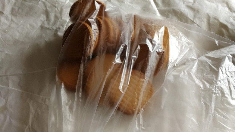 缤纷水果芝士派,饼干用保鲜袋装起来,用擀面杖敲打碎。