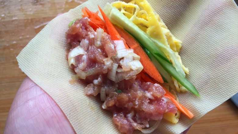 豆腐卷,把肉馅、鸡蛋丝、胡萝卜丝和黄瓜丝分别放在千张上,卷起来。