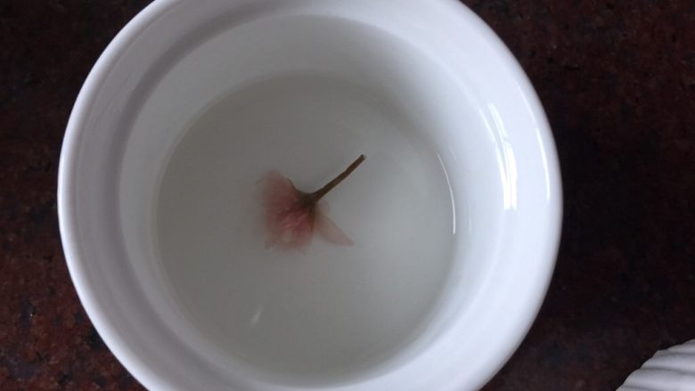 樱花双色布丁,将煮好的白凉粉放入烤碗中,放入泡发后的樱花,用牙签挑出花型