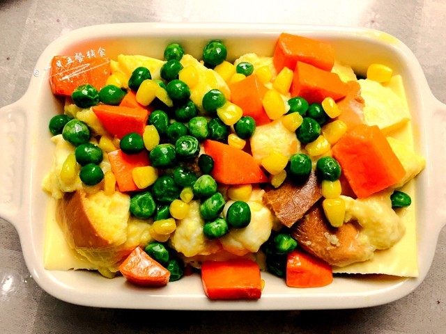 时蔬芝心面包布丁,将剩余的吐司丁全铺上，剩余蛋奶液均匀淋在吐司丁上。剩下的时蔬也均匀的洒在表面🌻小贴士：这里多余的蛋奶液一定要倒进来哦，烤好了就是幼嫩的布丁