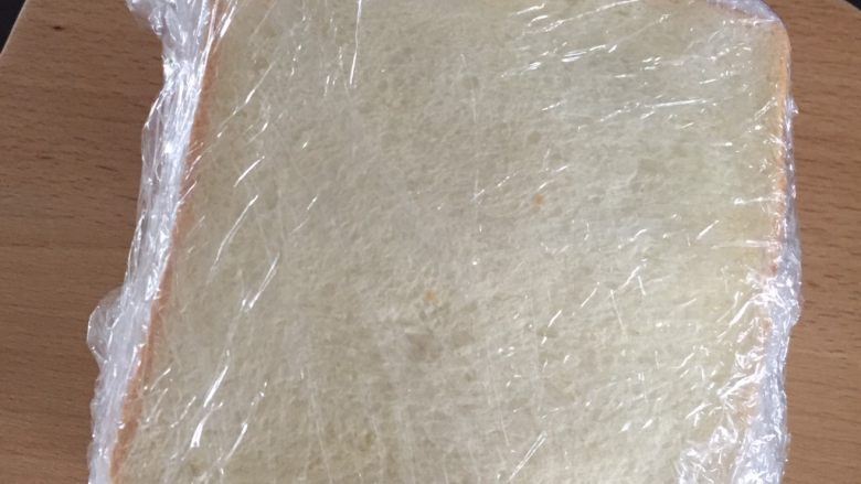 三明治里的爱马仕--厚吐司, 最后铺上挤了沙拉的吐司,把保鲜膜密实的包裹起来,由中间切开。