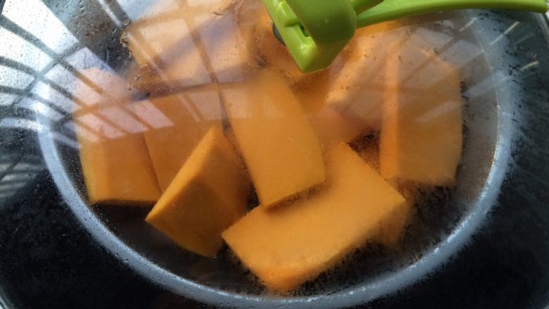 南瓜蜜豆肉松包,锅中放入适量的水,放入南瓜大火蒸至熟透,取出放凉。