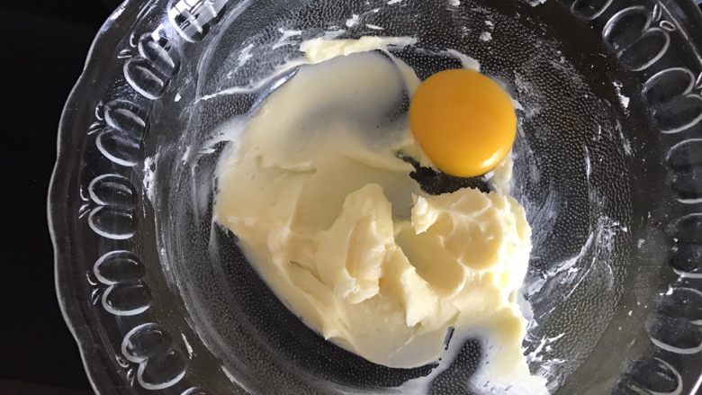 小乌龟菠萝包,翻拌均匀的黄油加入一个蛋黄,开动电动打蛋器低速打发。