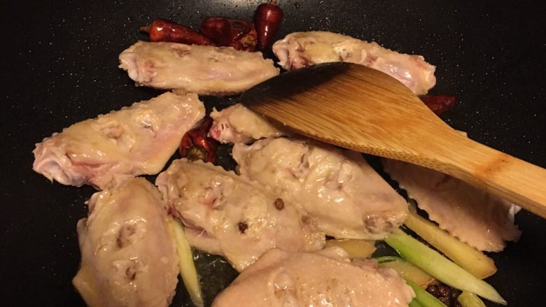红烧鸡翅,热锅下油放入葱姜花椒干辣椒炒香，然后下入准备好的鸡翅，煎到两面焦黄，煎的时候放适量<a style='color:red;display:inline-block;' href='/shicai/ 718'>料酒</a>，这个是刚下锅的时候拍的，要再多煎一会儿