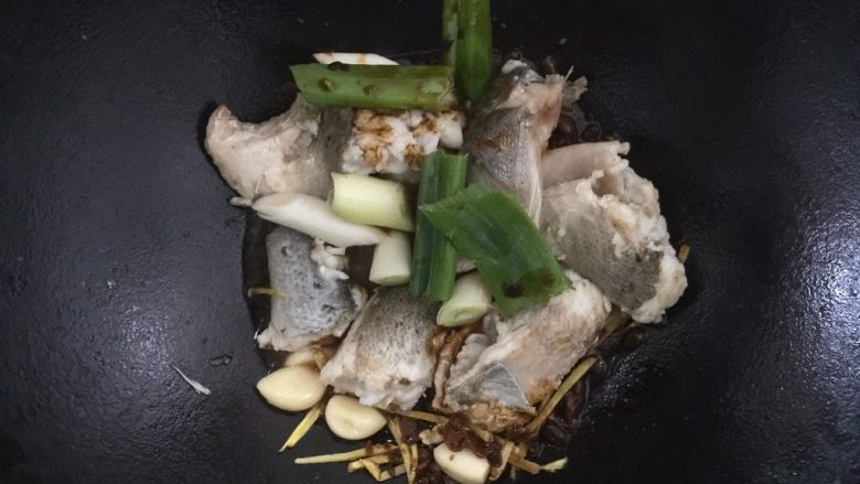 酱烧海鲈鱼,下葱段,倒入调料汁,等待一分钟,使其香味充分散发出来。