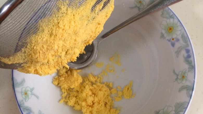蔓越莓玛格丽特,把鸡蛋黄放入面粉筛,用勺压成粉状。