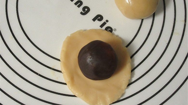 教你不用模具也可自制纯手工DIY月饼,随便取适量一小块的皮在手中捏扁,放上馅料,用虎口小心的把面皮往上推,整理好收口,不能有缝隙,并搓圆。