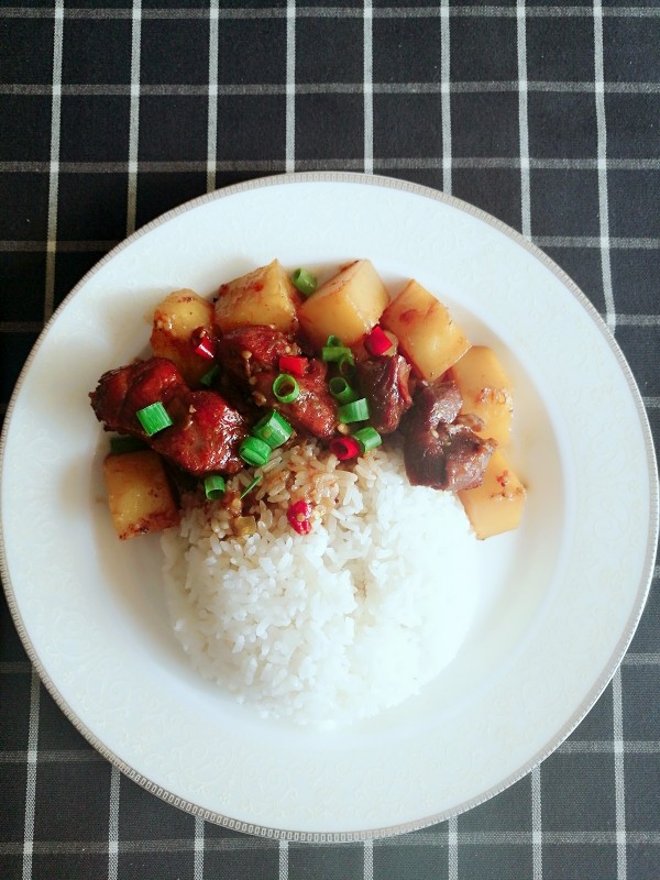 土豆排骨浇饭,收汁的土豆排骨浇在米饭上,撒上一点葱花就可以开吃了!