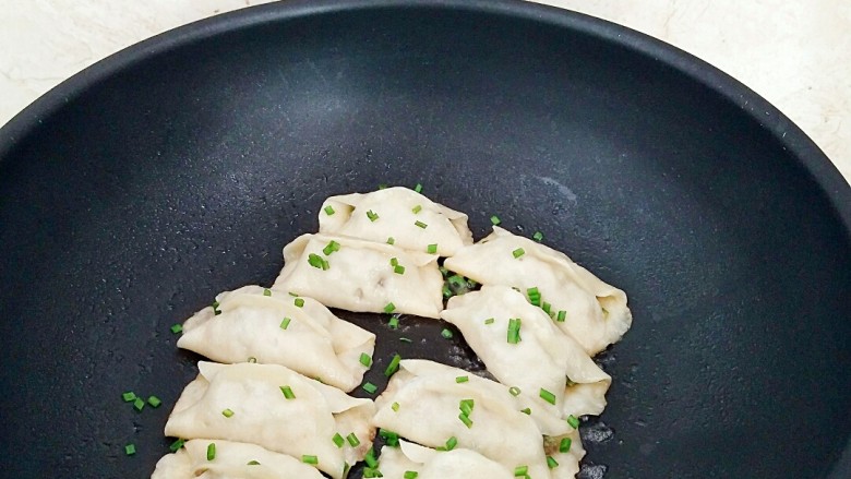 鲜肉豆角锅贴,水分收干，在撒上适量香葱碎即可出锅。