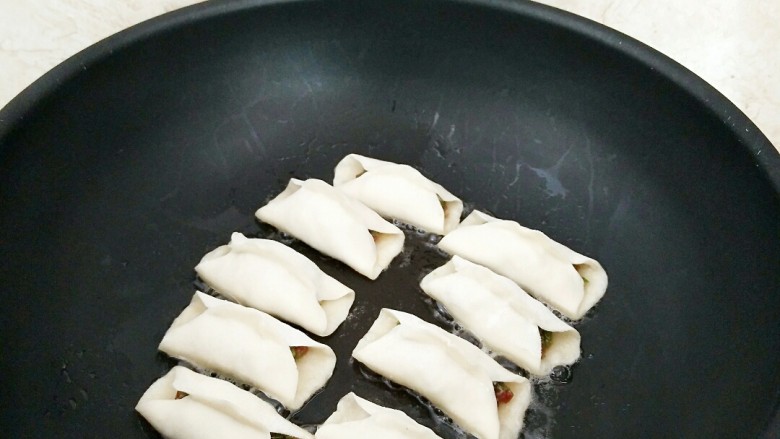 鲜肉豆角锅贴,锅中放油烧热,摆放锅贴,小火加热。