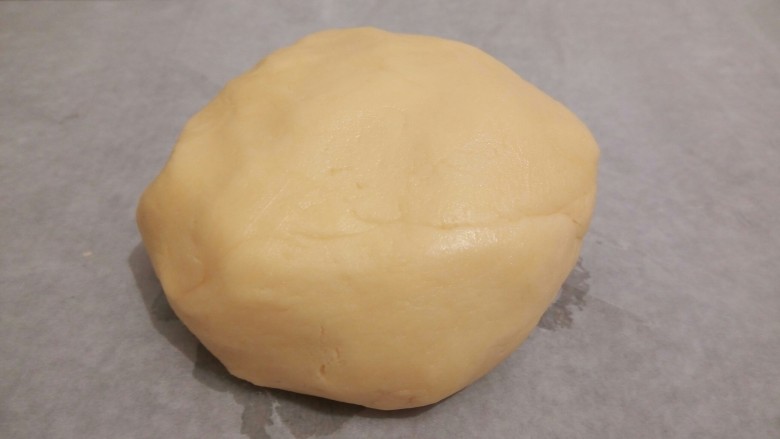 手工diy饼干,用橡皮刮刀,搅拌均匀,再用手给它揉成一个光滑的面团,放在油纸上